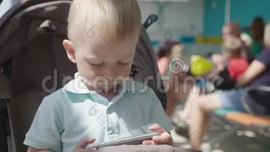 小男孩从智能手机看视频。 孩子们玩智能手机。 休闲、儿童、技术、互联网